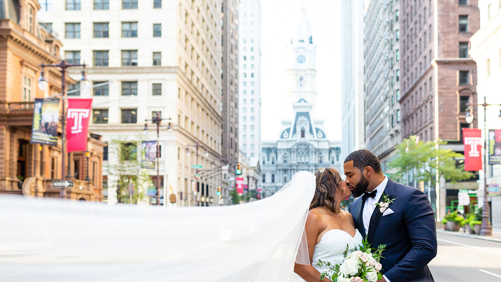 Bride and groom kissing on Broad Street in front of Philadelphia’s city hall building