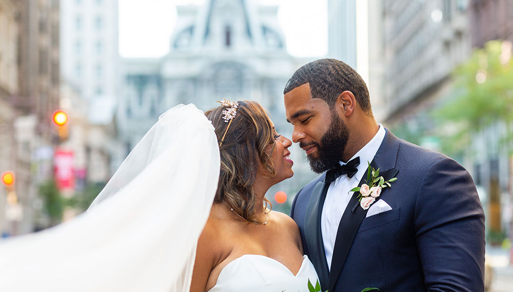 Bride and groom kissing in front of Philadelphia's City Hall building exterior
