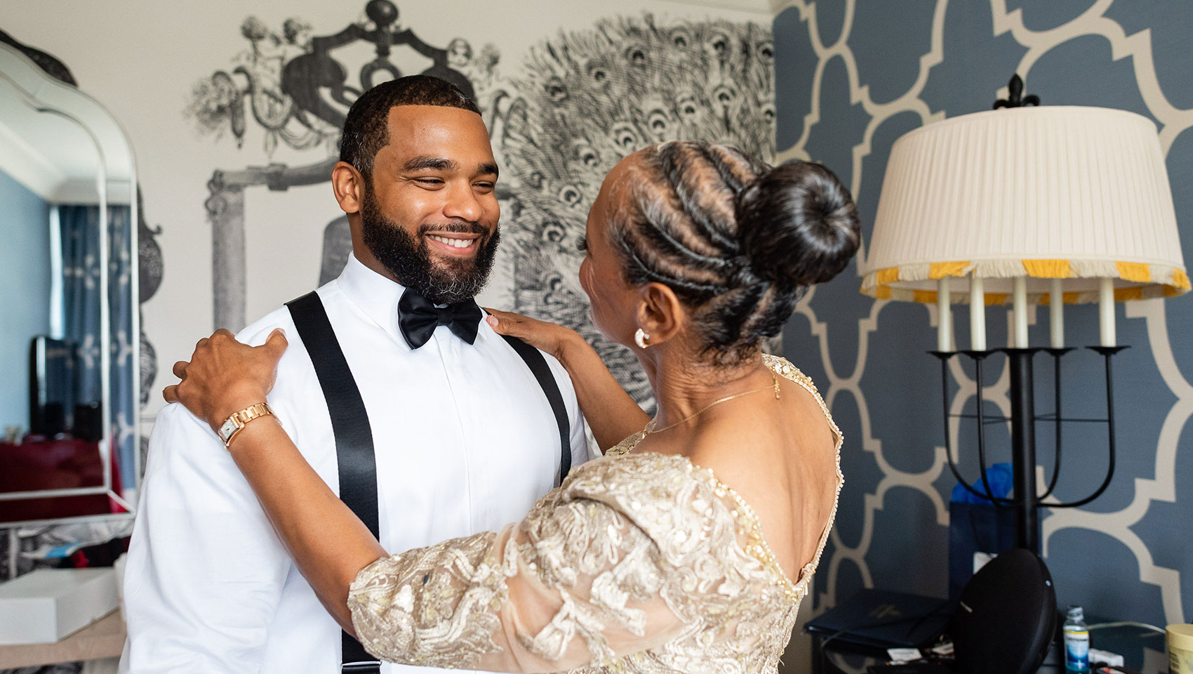 Groom getting ready with woman holding his shoulders lovingly