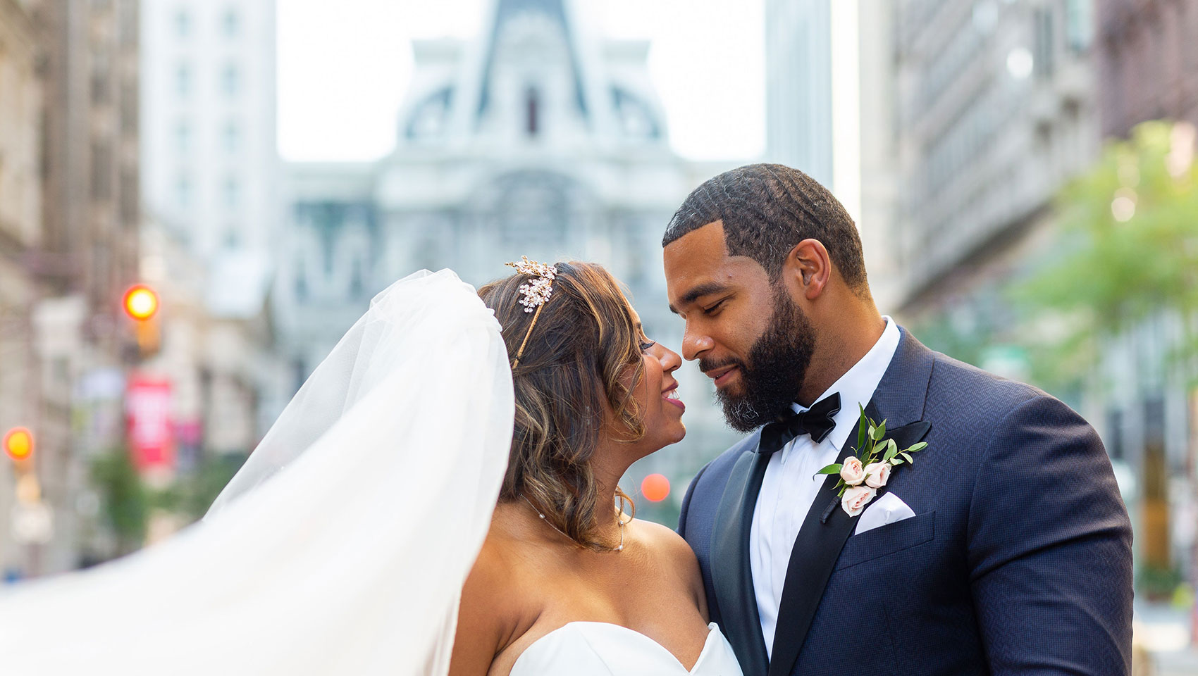 Bride and groom kissing in front of Philadelphia’s City Hall building exterior