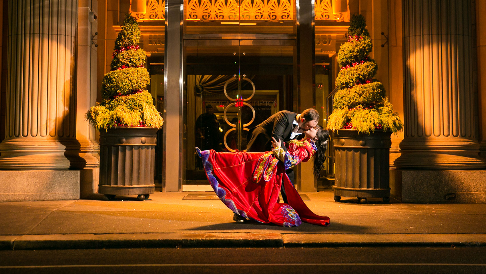 Bride and groom kissing in front of Kimpton Hotel Monaco Philadelphia main entrance