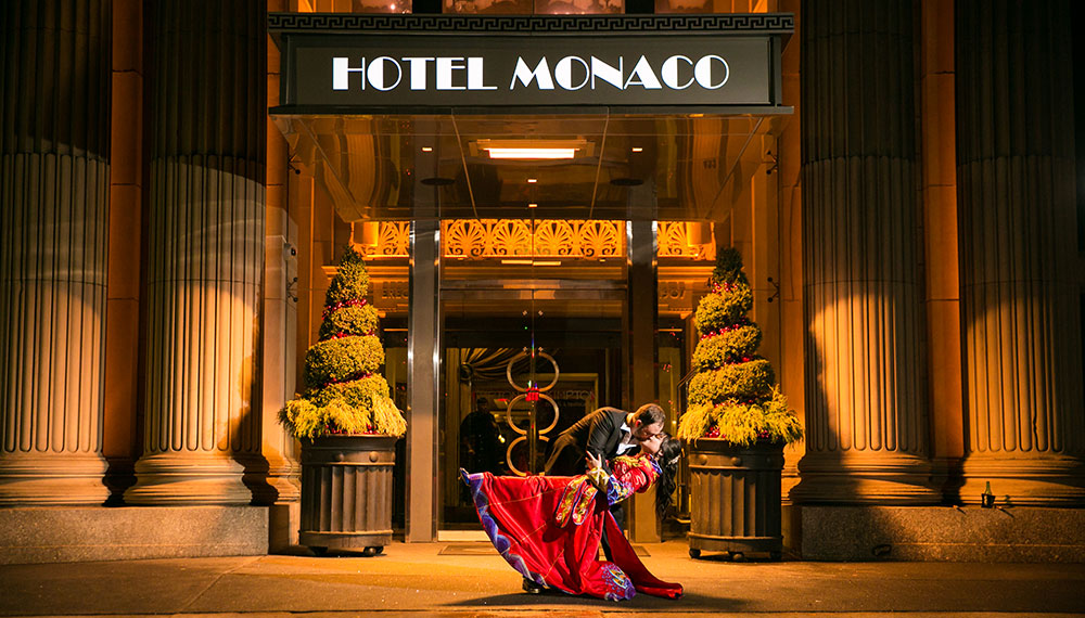 Bride and groom kissing in front of Kimpton Hotel Monaco Philadelphia main entrance