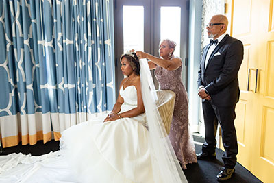 Bride’s veil being adjusted by woman and man