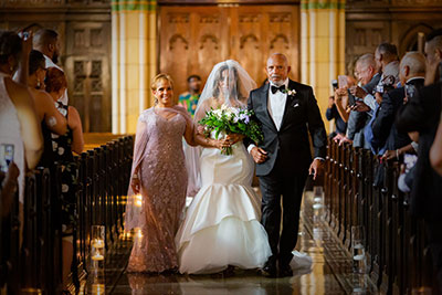 Bride being walked down the aisle by woman and man