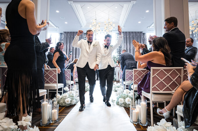 Grooms celebrating as they walk back up the aisle