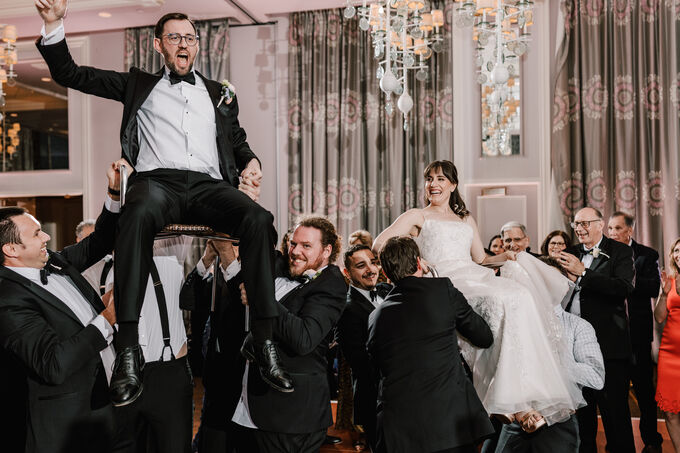 Bride and groom lifted on chairs during the hora