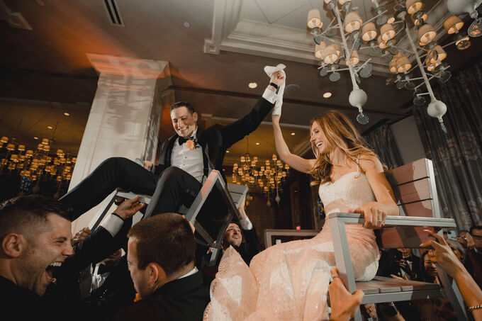 Bride and groom lifted on chairs during the hora