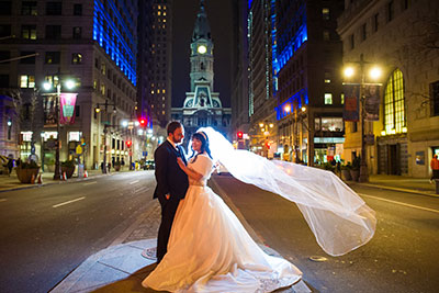 Bride and groom on Broad Street in Philadelphia in front of City Hall building