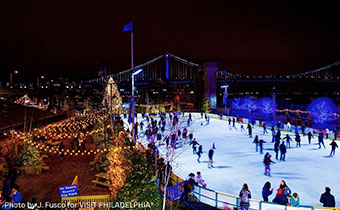Ice skaters at ice rink at night with holiday décor and lights
