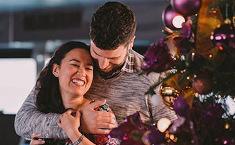 a couple embraces in front of holiday decor