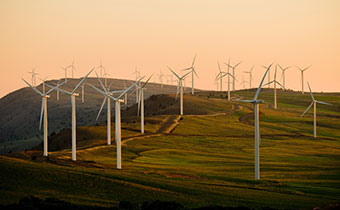 Wind turbines on hillside at sunset